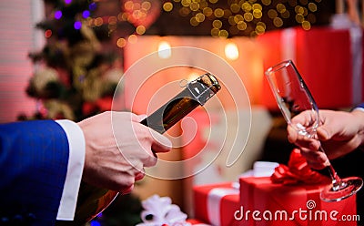 Male hands opening champagne bottle pouring glasses christmas decorations background. Drink champagne or sparkling wine Stock Photo