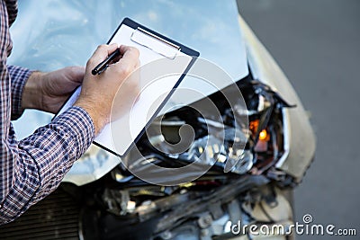 Male hands with paper mock up auto insurance blank against Destroyed car in car crash traffic accident on road. Smashed broken Stock Photo