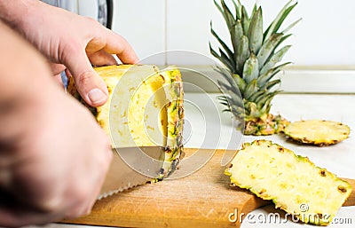 Male hands peeling fresh pineapple skin Stock Photo