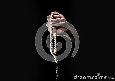 Male hands praying using prayer beads over dark backgroud Stock Photo