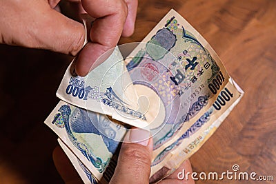 Male hands showing banknotes from Japan on a wooden background Stock Photo