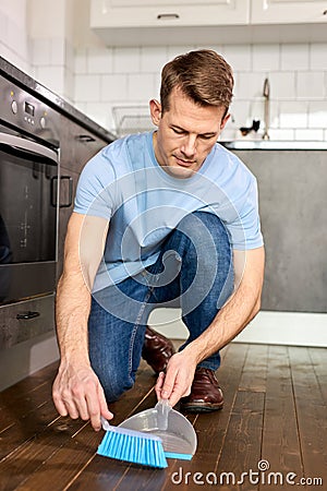 Male Hands Sweeping Dust With Broom On Dustpan, Housekeeping Concept, Close-up Photo Stock Photo
