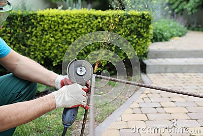 male hands in thick protective gloves cut an iron rod, sparks fly close-up. Cutting a metal rod with a burst of sparks Stock Photo