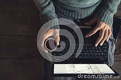 male hands using Laptop and coffee cup in hands sitting on a wooden floor Stock Photo