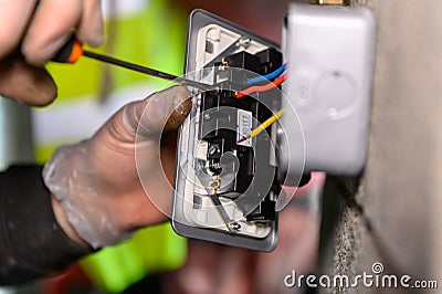 Male hands wiring a uk socket plug on garage wall with screw driver Stock Photo