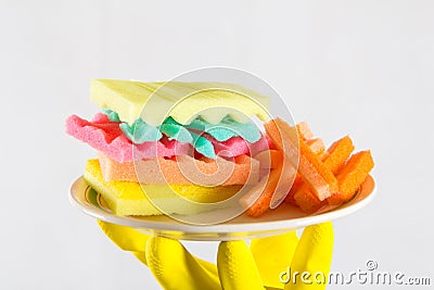 Male hands in yelliw gloves holding a burger made from sponges different colors. Concept of unhealthy food and non Stock Photo