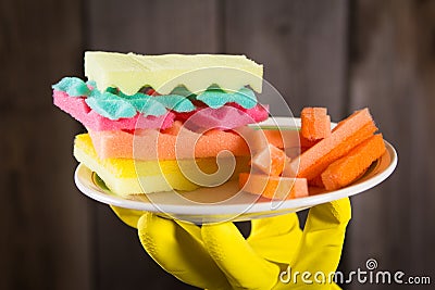 Male hands in yelliw gloves holding a burger made from sponges different colors. Concept of unhealthy food and non Stock Photo