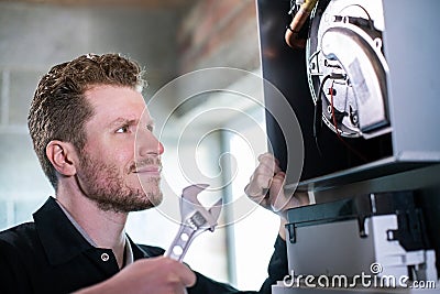 Male Heating Engineer With Adjustable Wrench Servicing Boiler Stock Photo
