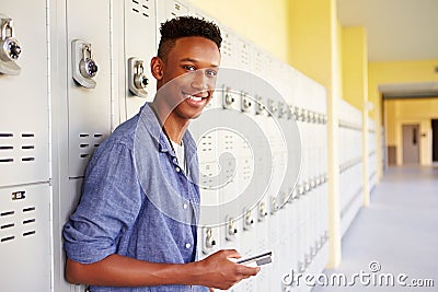 Male High School Student By Lockers Using Mobile Phone Stock Photo