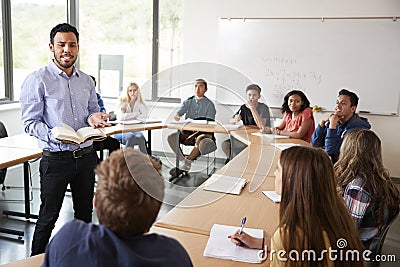 Male High School Tutor With Pupils Sitting At Table Teaching Maths Class Stock Photo