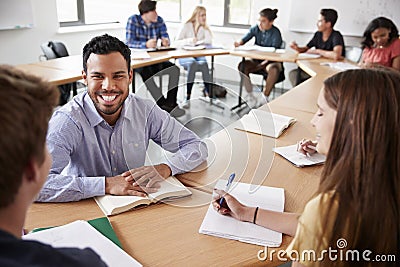 Male High School Tutor With Pupils Sitting At Table Teaching Maths Class Stock Photo