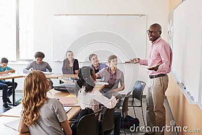 Male High School Tutor Standing At Whiteboard Teaching Class Stock Photo