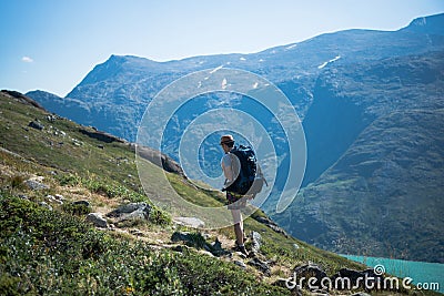 male hiker with backpack walking on Besseggen ridge over Gjende lake in Jotunheimen National Stock Photo
