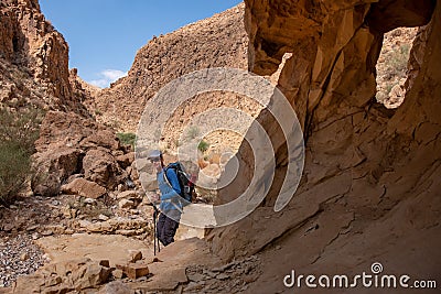 Male hiker going through a narrow deep canyon of dry wadi Abuv in Judean Desert close to city Arad, Israel. Editorial Stock Photo
