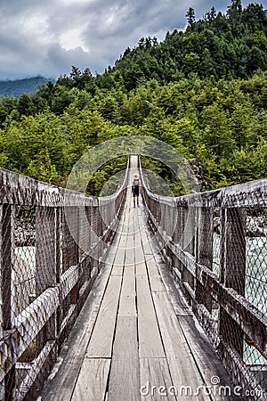 A male hiker on a wooden bridge over a river in Chile. Editorial Stock Photo