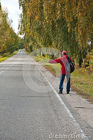 Male hitchhiker on autumn road Stock Photo