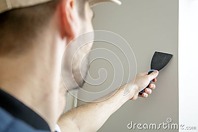 Male holds putty knife on the wall near the wall corner. Stock Photo