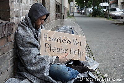 Male Homeless Sitting On A Street Asking For Help Stock Photo