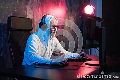 Male hooded gamer playing online game on pc computer Stock Photo