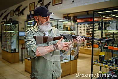 Male hunter reloads rifle in gun store Stock Photo