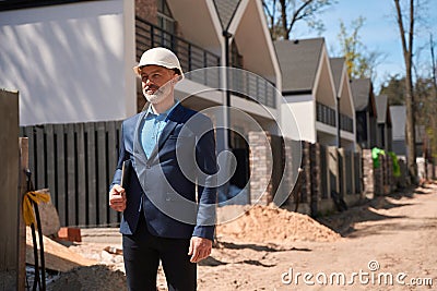 Male investor in businesssuit and hardhat holding laptop Stock Photo