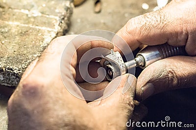 Jeweler polishing a ring using a sandpaper on a slotted mandrel. Stock Photo