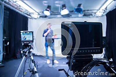 Journalist in a television studio is talking into a microphone, blurry film cameras Stock Photo