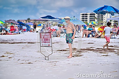 Male kid looking at the Rip Currents warning sign at the Siesta Beach in Sarasota, Florida Editorial Stock Photo