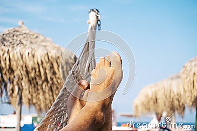 Male legs laying relaxed on hammock on tropical beach. Carefree. Stock Photo