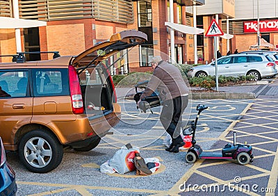 Male loading a diabled persons mobility scooter into the back of Editorial Stock Photo