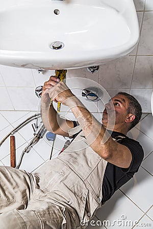 Specialist male plumber repairs faucet in bathroom Stock Photo