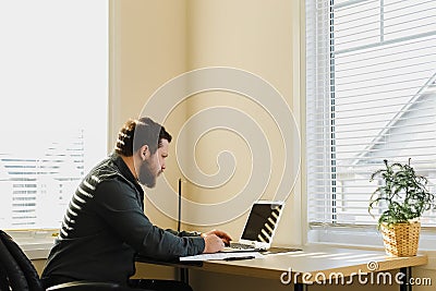 Male manager sitting at desk and using laptop at cabinet. Stock Photo