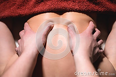 Male masseur doing back massage to client woman in dark room of massage spa Stock Photo