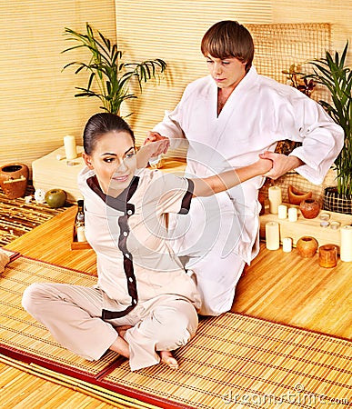 Male masseur doing massage woman in bamboo spa. Stock Photo