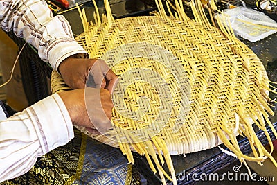 Male master hands weaves straw hat. Stock Photo