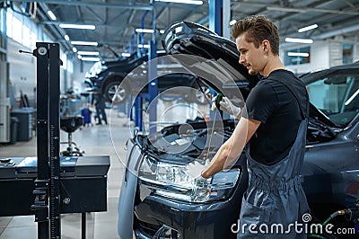 Male mechanic adjusts the headlights, car service Stock Photo