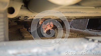 Male mechanic underneath a car reaching for a screwdriver in garage Stock Photo