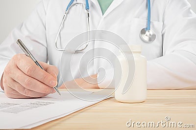 Male medicine doctor hand hold jar of pills and write prescription to patient at worktable. Panacea and life save prescribing Stock Photo