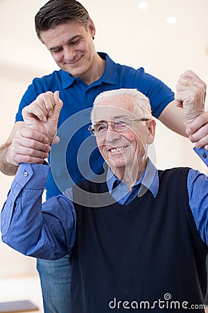 Male Nurse Assessing Senior Stroke Victim By Raising Arms Stock Photo