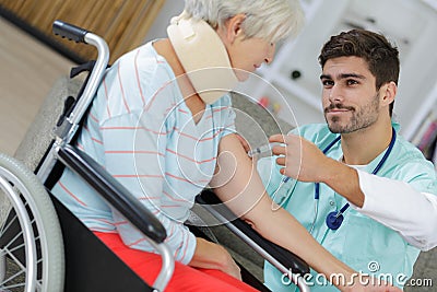 Male nurse giving vaccine injection to elderly woman Stock Photo