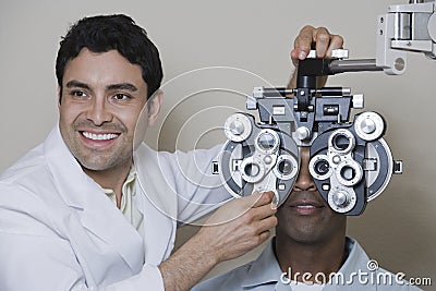 Male Optometrist Adjusting Panels Of Phoropter Stock Photo