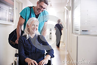 Male Orderly Pushing Senior Female Patient Being Discharged From Hospital In Wheelchair Stock Photo