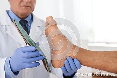 Male orthopedist fitting insole on patient`s foot in clinic Stock Photo