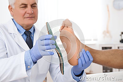 Male orthopedist fitting insole on patient`s foot Stock Photo