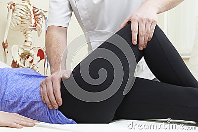 Male Osteopath Treating Female Patient With Hip Problem Stock Photo