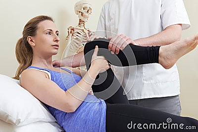 Male Osteopath Treating Female Patient With Hip Problem Stock Photo