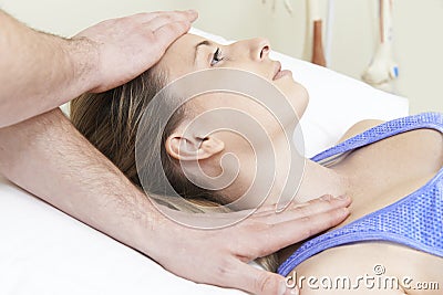 Male Osteopath Treating Female Patient With Neck Problem Stock Photo