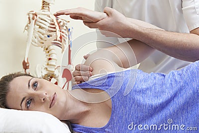 Male Osteopath Treating Female Patient With Shoulder Problem Stock Photo