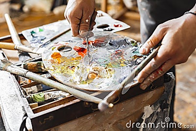 Male painter at art studio indoors mixing colors on palette close-up Stock Photo