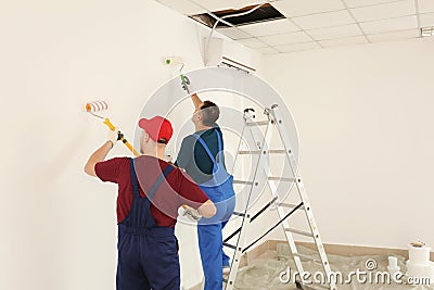 Male painters in uniform working indoors Stock Photo